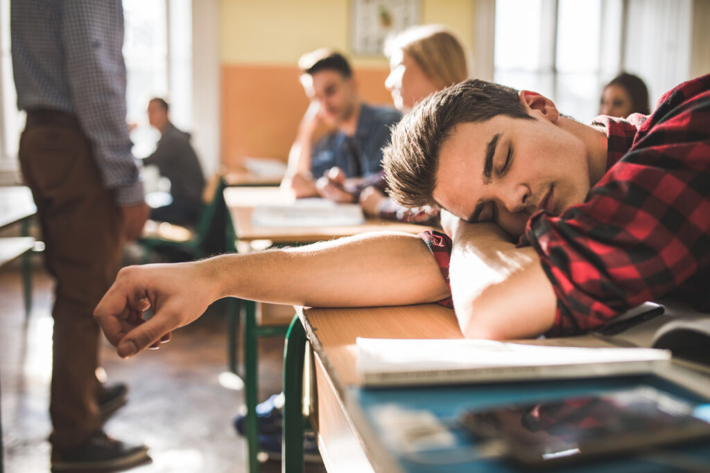 Male student at school asleep with head on deskl