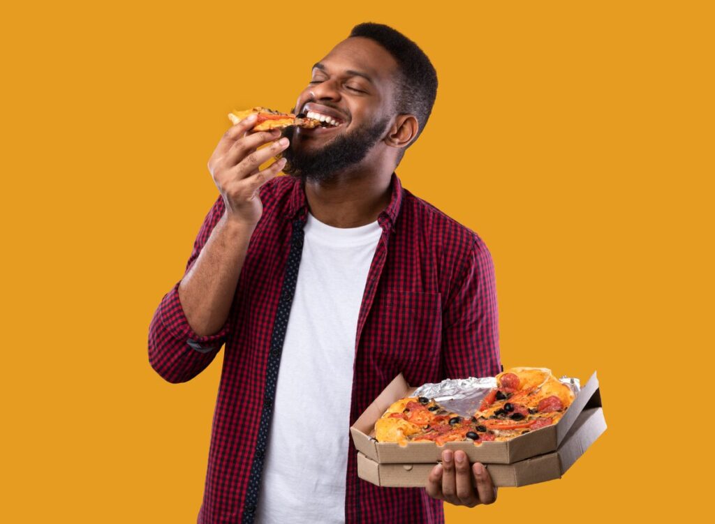 Man eating pizza from cardboard pizza box that may contain PFAS