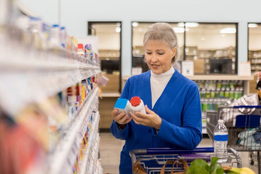 Older woman in pharmacy comparing medication ingredients 