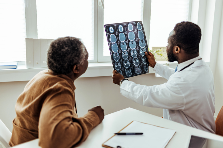 A male doctor and his patient examine a brain MRI.