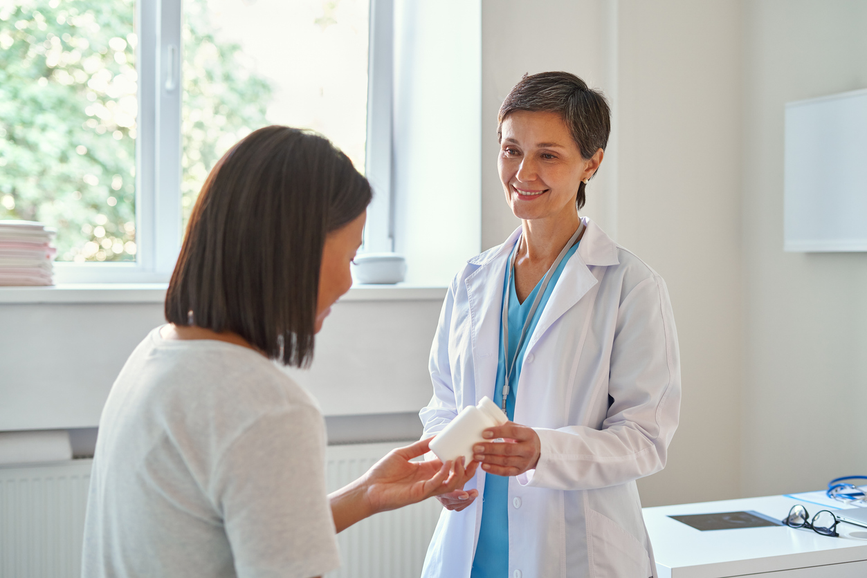 female nurse giving medication bottle to female patient