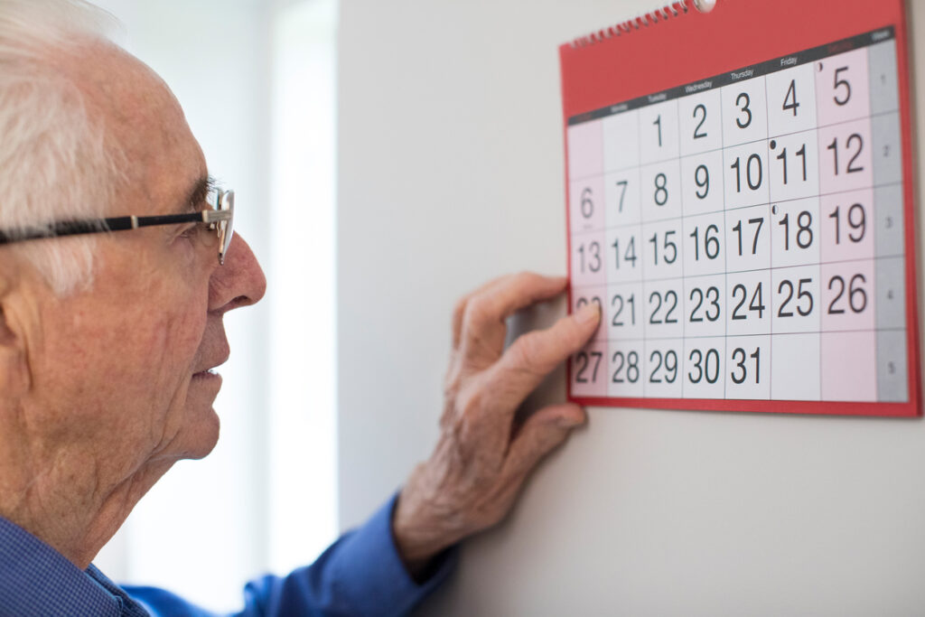 Man looking at wall calendar. Visual tools are helpful for both dementia patients and those who provide care for someone with dementia.