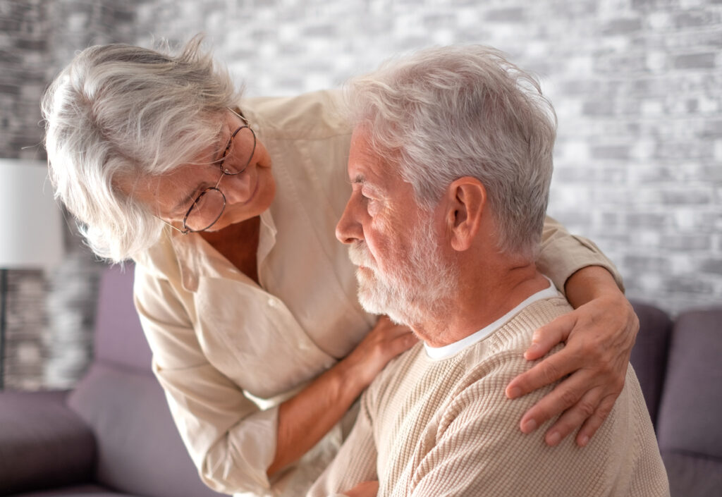 Concerned older woman with arm around older man who looks confused. 