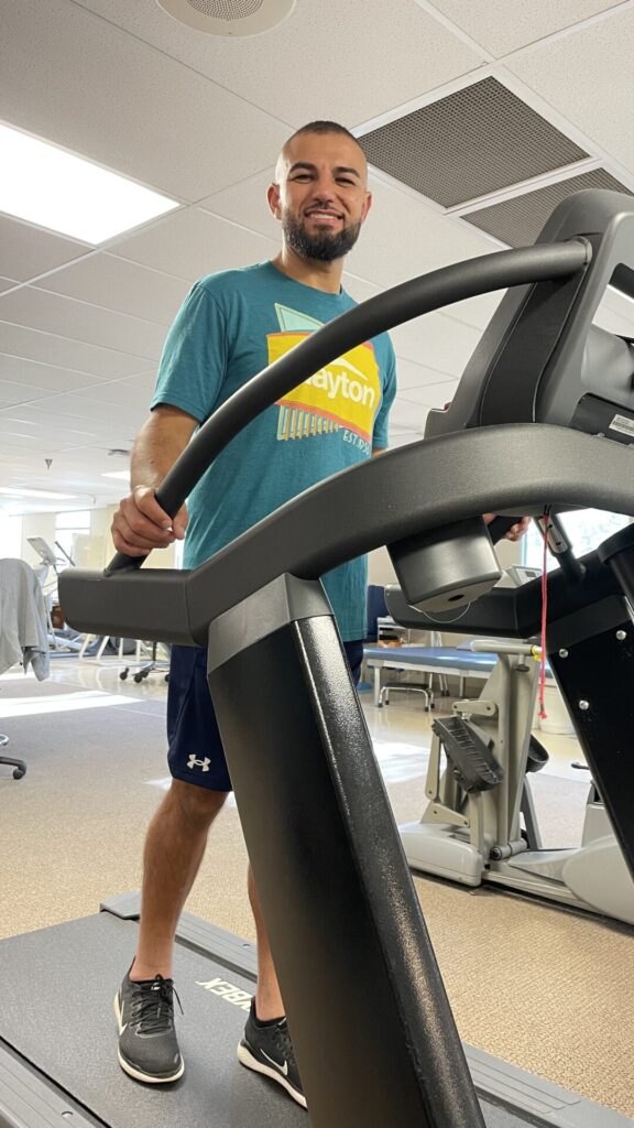 Smiling man walking on treadmill.