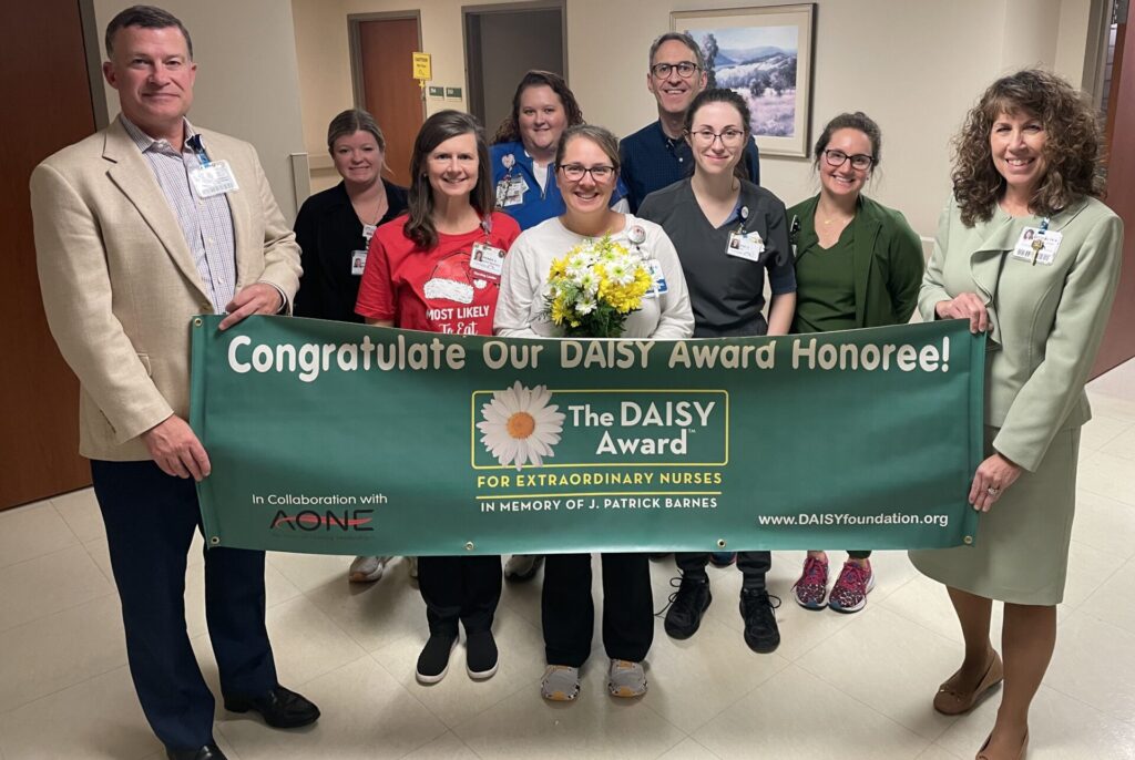 Group of people with DAISY award banner. Recipient Christy Bright is in the center of the group.