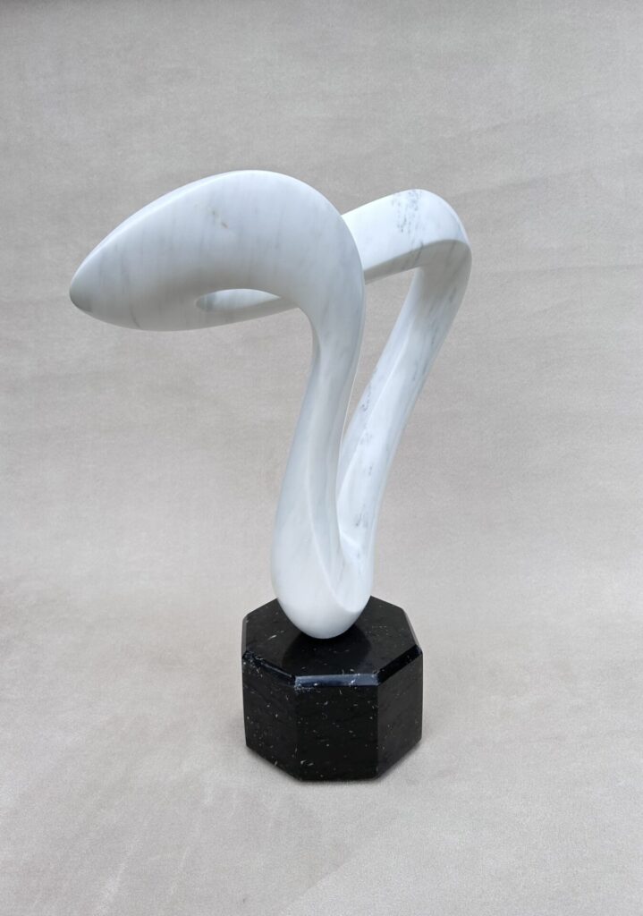 White marble sculpture on black base created by Bill Cook, Jr., for Artsclamation! fine art sale. 