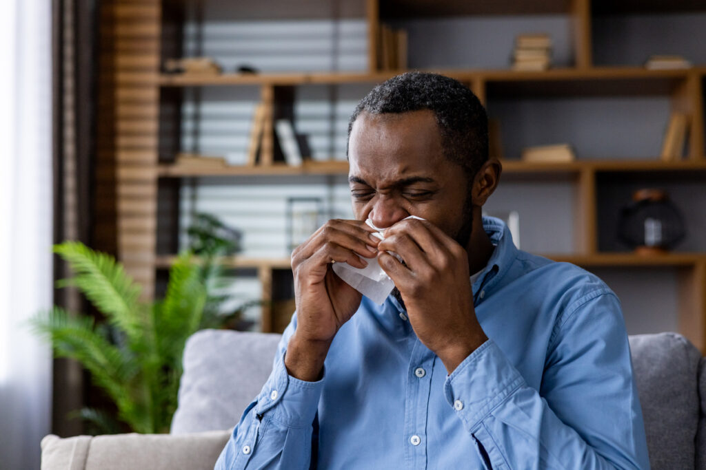 Black man sitting in chair and sneezing 