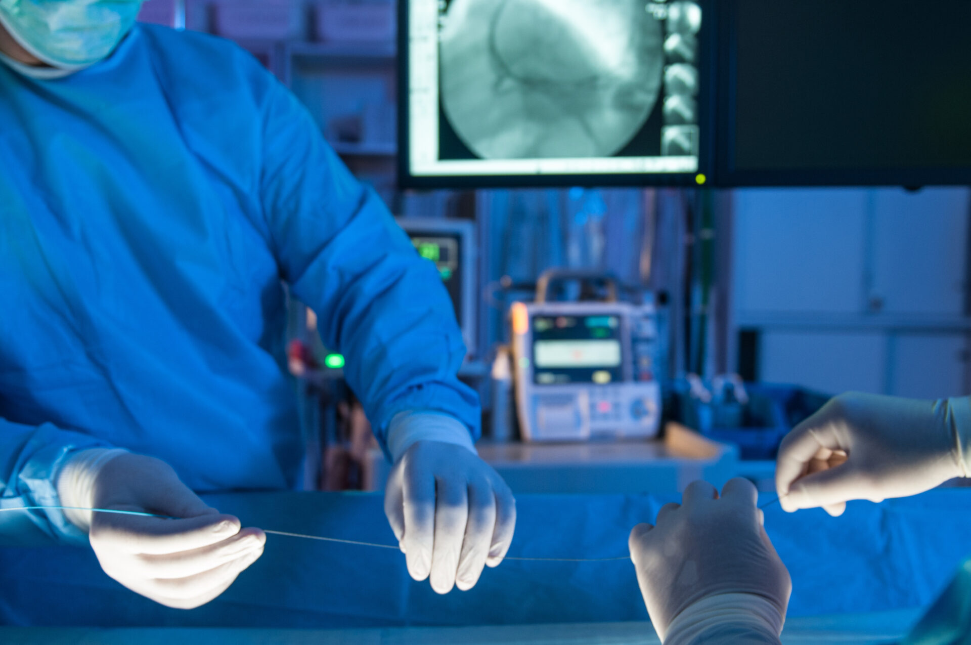 Close up of two interventional heart surgeons in an operating room holding a heart stent.