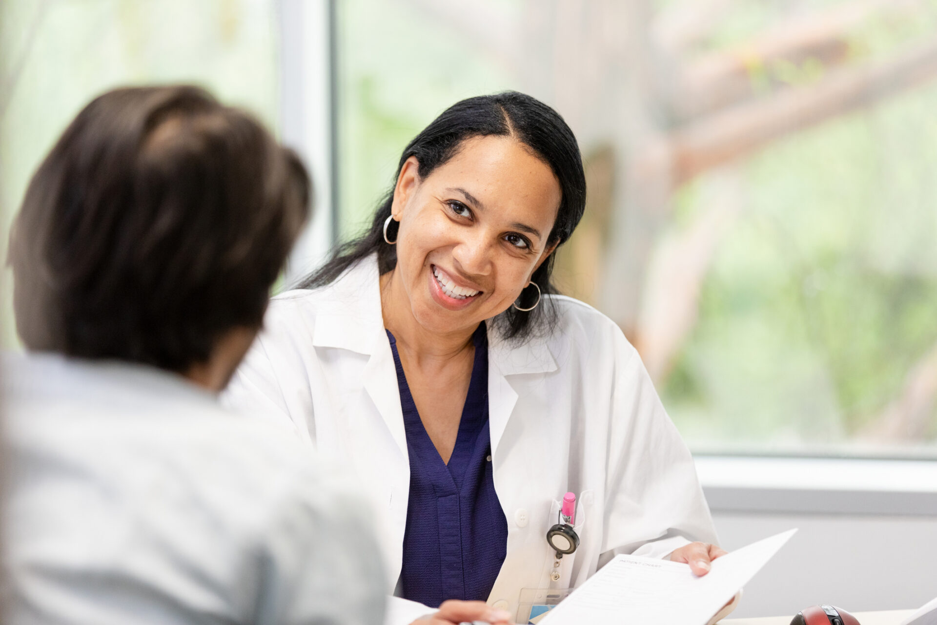 The female doctor smiles while giving her unrecognizable male patient some good news about the test results from his most recent appointment.