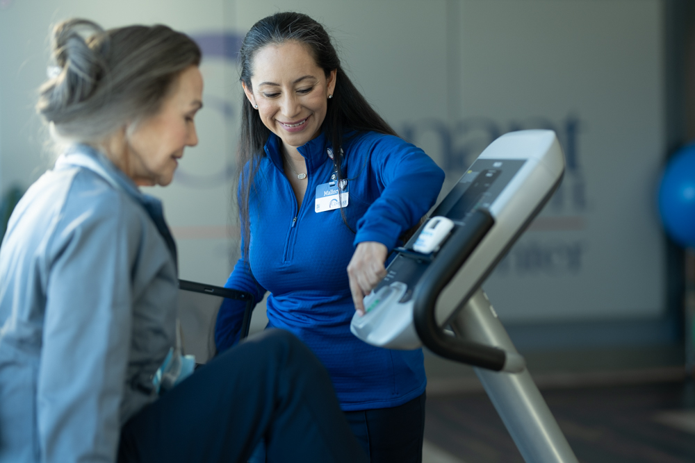 A Covenant Health physical therapist adjusts settings on a stationary bike for her patient.