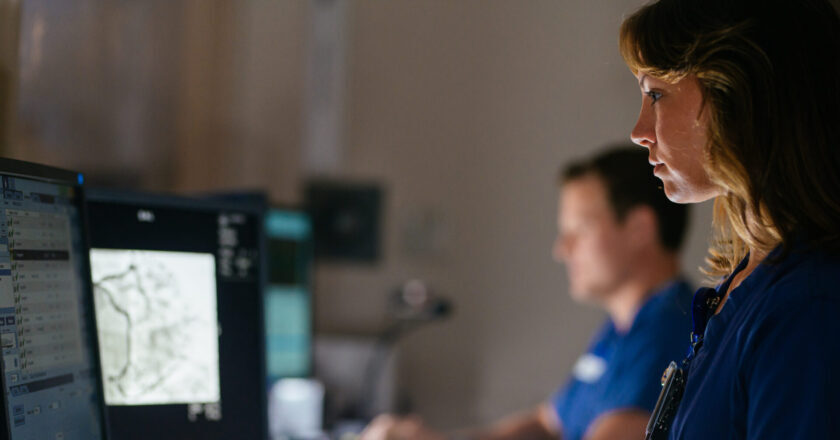 A physician and her colleague examine test results on the computer in a cardiac cath lab.